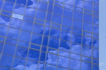 Plakat Blue windows of a building with clouds reflected in them against a cloudy sky