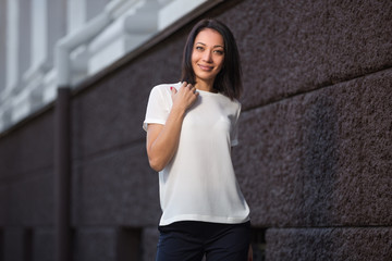 Happy young fashion woman in white t-shirt on city street