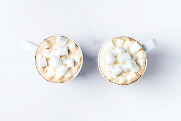 Romantic cozy desk top with two cups of coffee with marshmallows on marble table. Top view. Space for text .