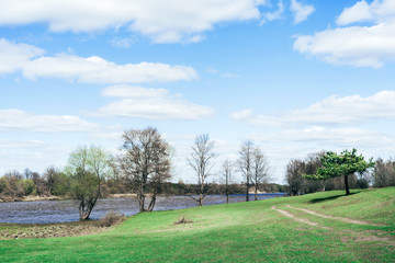 Beautiful brightly lit spring landscape background. Blue river and trees on on a sunny day after melting snow.