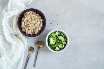 Bowl of rice with spices and vegetable salad on a gray background