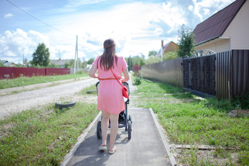 Young mother walking with a baby in a stroller