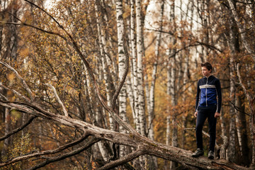 Young man standing on fallen tree