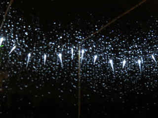 Naklejka na ściany i meble Regentropfen am Fenster mit Lichtern im Hintergrund