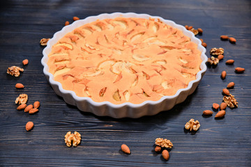 Home baking ripe apples on black wooden background. Apple pie with walnuts and almonds. Fruit cake with nuts.