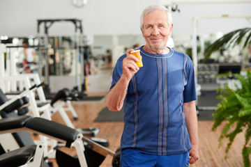 Senior man with pills at gym. Senior man with bottle of supplement at fitness studio. People, sport...