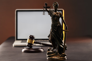 Statue of Justice and judje gavel. Laptop behind