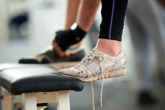 Female feet in sneakers in gym close up. Cropped image of womans leg in running shoes with untied laces at fitness club. People, fitness, active lifestyle concept.