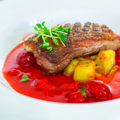 fried duck breast with berry sauce and vegetables (main dish). food background. top