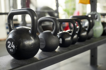Row of kettlebells at gym. Black kettlebells at fitness club. Modern equipment for functional training.