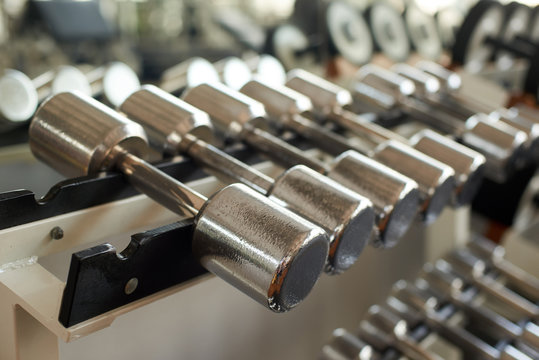 Rows of dumbbelss set close up. Training equipment in fitness club. Gym equipment background.
