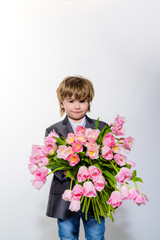 Little boy with pink tulips. Cute small kid holds bouquet of tulips. Boy with flowers in hands. Toddler boy in suit hold tulips. Cute gentleman boy presenting bouquet of tulips. Valentines day. Spring