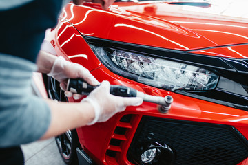 Car detailing - Worker with orbital polisher in auto repair shop.