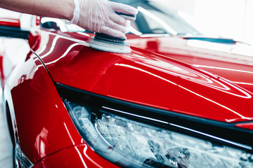 Car detailing - Worker with orbital polisher in auto repair shop.