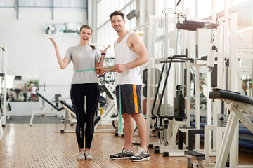 Fitness trainer measuring female waist at gym. Young successful woman happy of her weight loss....