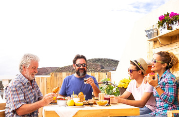 Family group of caucasian people. Having together happy breakfast outdoor in the terrace. Wooden table.Bright background. Three adult and one teenager.