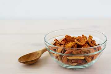 Homemade dried apples in a bowl on a wooden table. Vertical orientation, with copy space