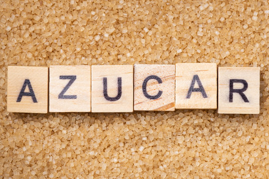 Word "azucar" on scrabble uppercase letters over a brown sugar surface