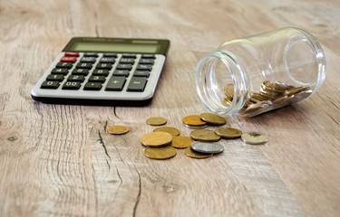 Ukrainian coins in a jar and calculator on the background of a wooden table