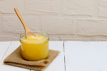 Ghee butter or clarified butter on white background with wooden spoon, copy space