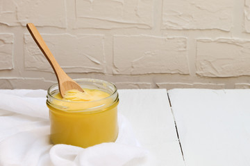 Ghee butter or clarified butter on a table with wooden spoon, copy space