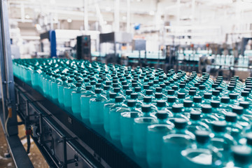 Fototapeta premium Bottling plant - Water bottling line for processing and bottling pure spring water into small bottles. Selective focus.