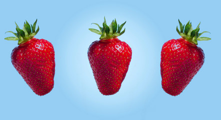 Three fresh strawberries on blue background 