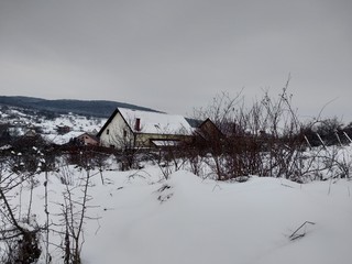 Paisaje de invierno con montañas y árboles, casas pueblo rural nieve en Rumanía Transilvania © nykaly