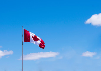 Flag of  Canada isolated against a blue sky with white clouds