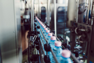 Fototapeta premium Bottling plant - Water bottling line for processing and bottling carbonated water into bottles. Selective focus.