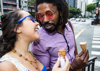 Romantic Multiracial couple sharing in the streets ice cream cone.