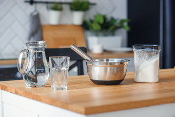 Kitchen utensils for dough preparation. A bank with water, a metal plate and a flour.