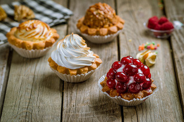 tartlets with fresh berries and lemon on wooden board