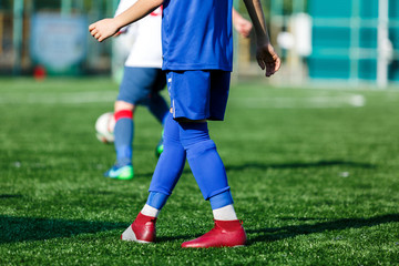 Obraz premium Junior football match. Boys in blue white sportswear play soccer match on football pitch. Football stadium, grass field at the background Soccer for young players. Training, sport, activity outdoor