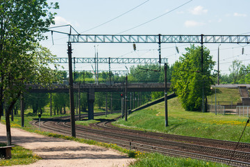 General view of the empty railroad tracks and road bridge over them in the summer during the time of flowering dandelions.