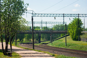 General view of the empty railroad tracks and road bridge over them in the summer during the time of flowering dandelions.