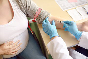 Doctor or paramedic makes analysis blood to a pregnant woman. Medical insurance childbearing....