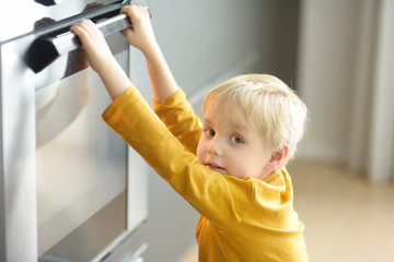 Charming boy waiting preparing food in domestic kitchen.