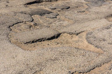 Big potholes on the damaged asphalt road