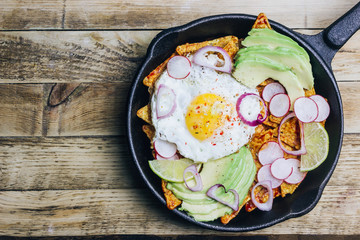 Homemade chilaquiles breakfast: nachos with tomato salsa, avocado and fried egg