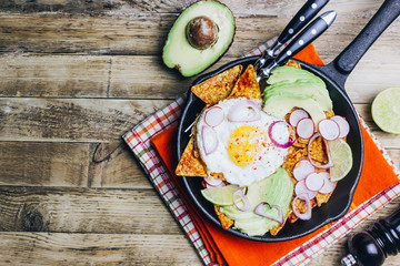 Homemade chilaquiles breakfast: nachos with tomato salsa, avocado and fried egg
