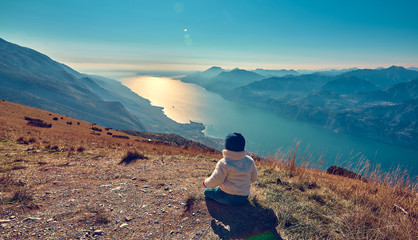 Nice little child admiring the beautiful Lake Garda from Monte Baldo, Panorama of the gorgeous...
