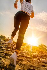 young fitness woman jogging at sunrise/sunset beach
