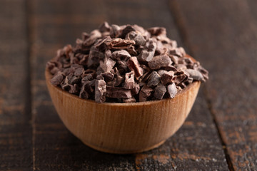 Bowl of Raw Chocolate Nibs on a Rustic Wooden Table