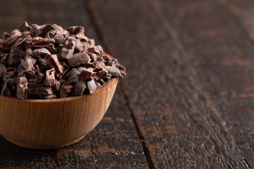 Bowl of Raw Chocolate Nibs on a Rustic Wooden Table