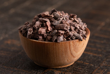 Bowl of Raw Chocolate Nibs on a Rustic Wooden Table