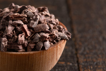 Bowl of Raw Chocolate Nibs on a Rustic Wooden Table