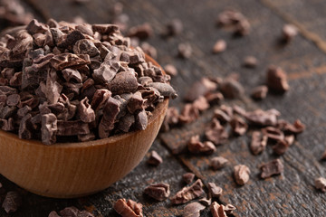Bowl of Raw Chocolate Nibs on a Rustic Wooden Table