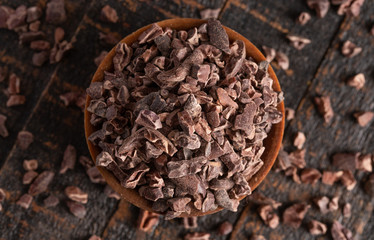 Bowl of Raw Chocolate Nibs on a Rustic Wooden Table
