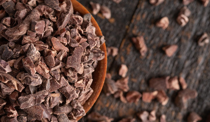 Bowl of Raw Chocolate Nibs on a Rustic Wooden Table